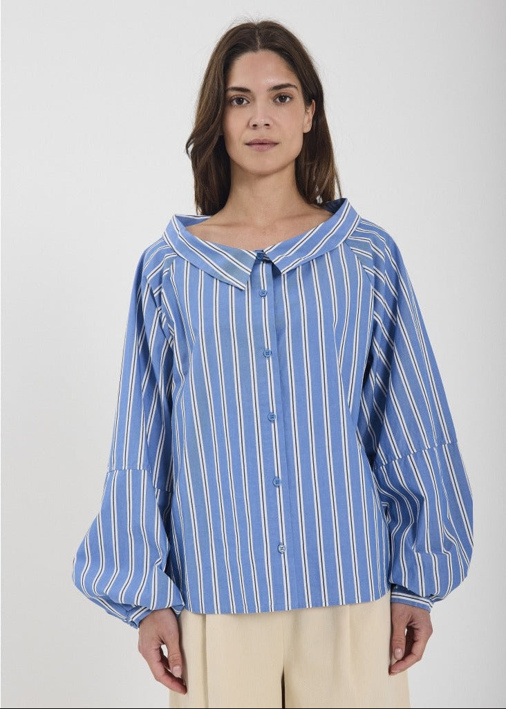 Woman wearing a blue and white striped shirt against a plain background