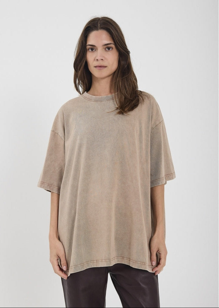 Woman wearing a beige oversized t-shirt on a white background