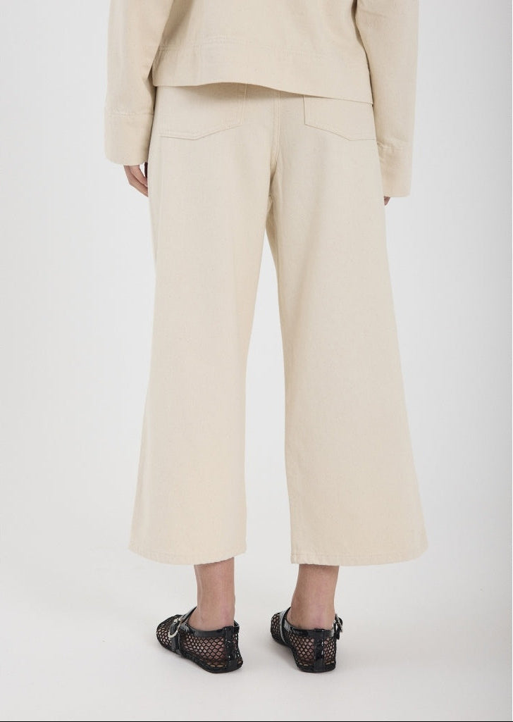 Person wearing beige pants and a matching top on a white background