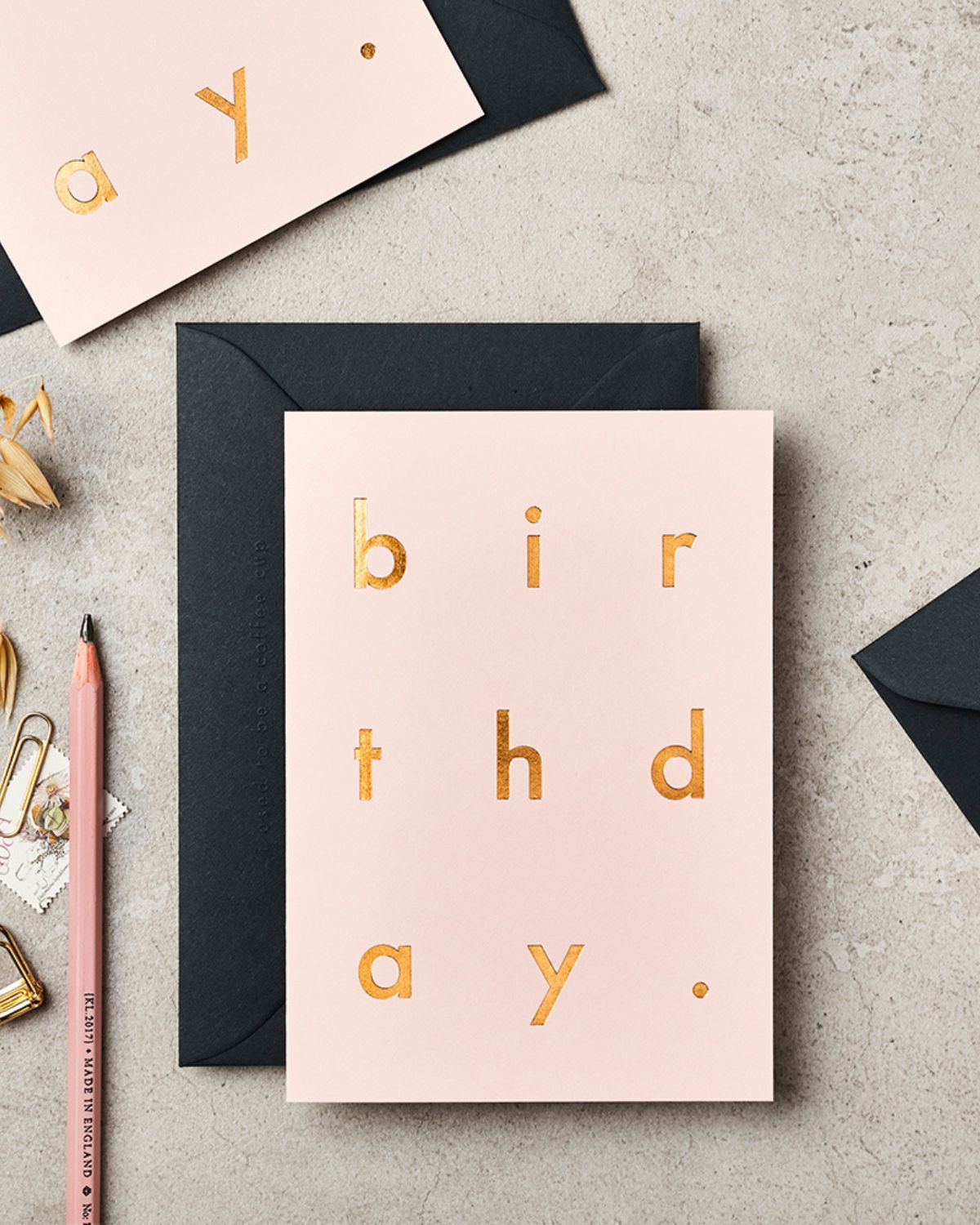 Pink birthday card with gold text on a gray surface