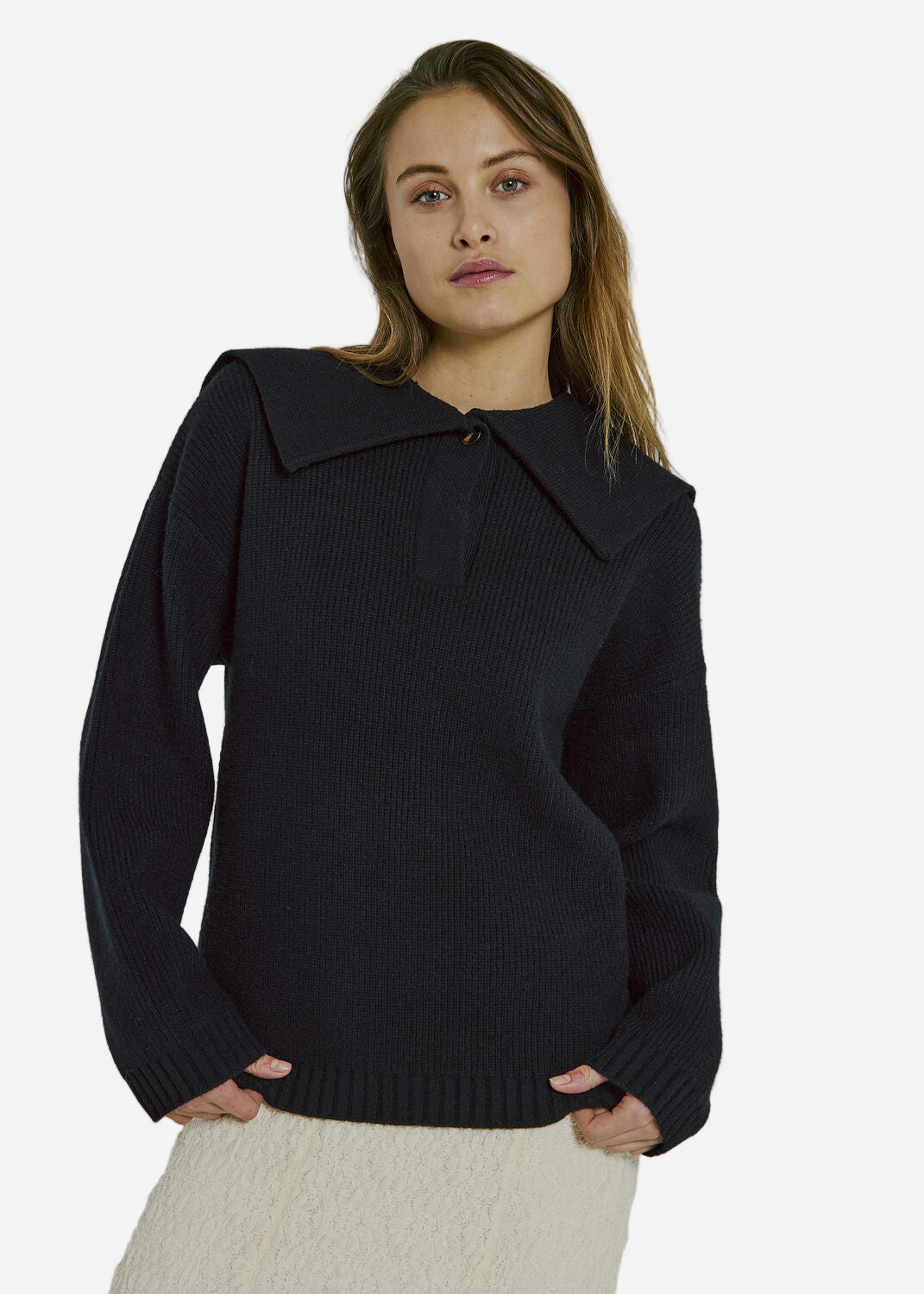 Woman wearing a black sweater with a collar against a gray background