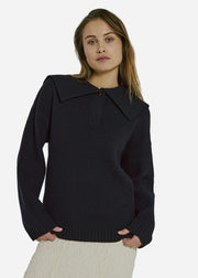 Woman wearing a black sweater with a collar against a gray background