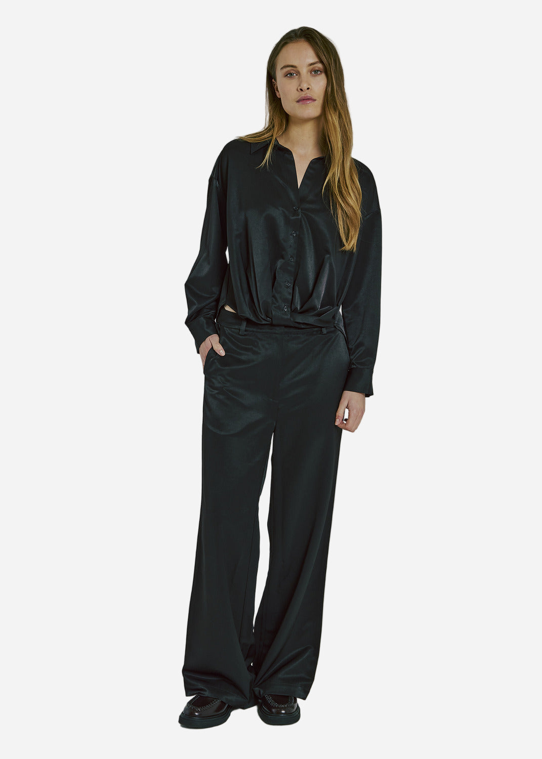 Woman wearing a black satin outfit on a plain background