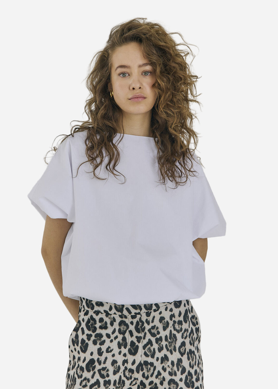 Person wearing a white t-shirt and leopard print pants on a plain background