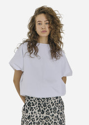 Person wearing a white t-shirt and leopard print pants on a plain background