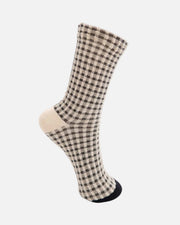 A single crew sock with a beige and black gingham check pattern, featuring solid beige heel and toe sections and a black heel cap, shown on a plain white background.