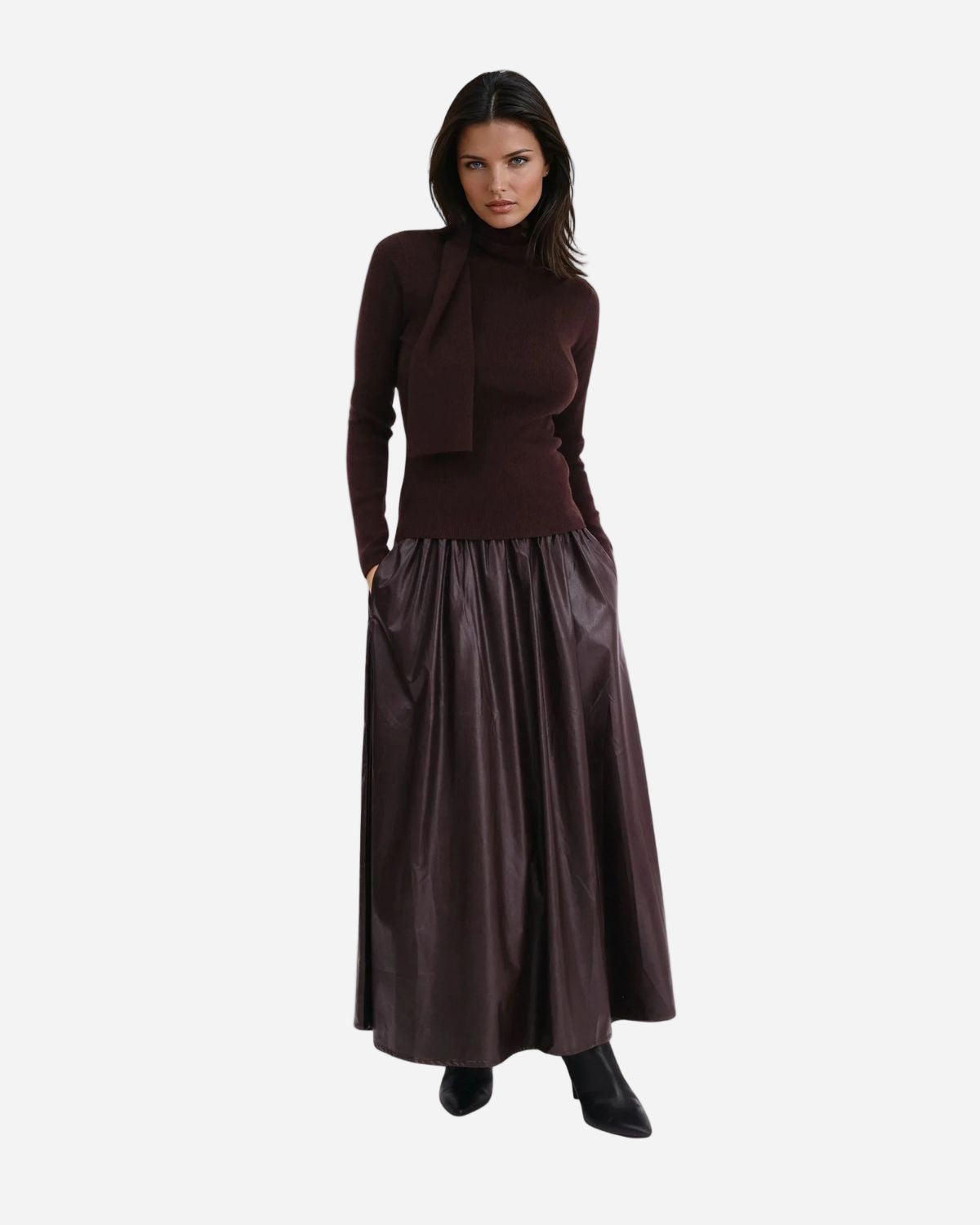 Woman wearing a dark brown turtleneck sweater and brown faux eather skirt on a white background