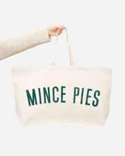 Beige tote bag with 'Mince Pies' text held by a person on a white background