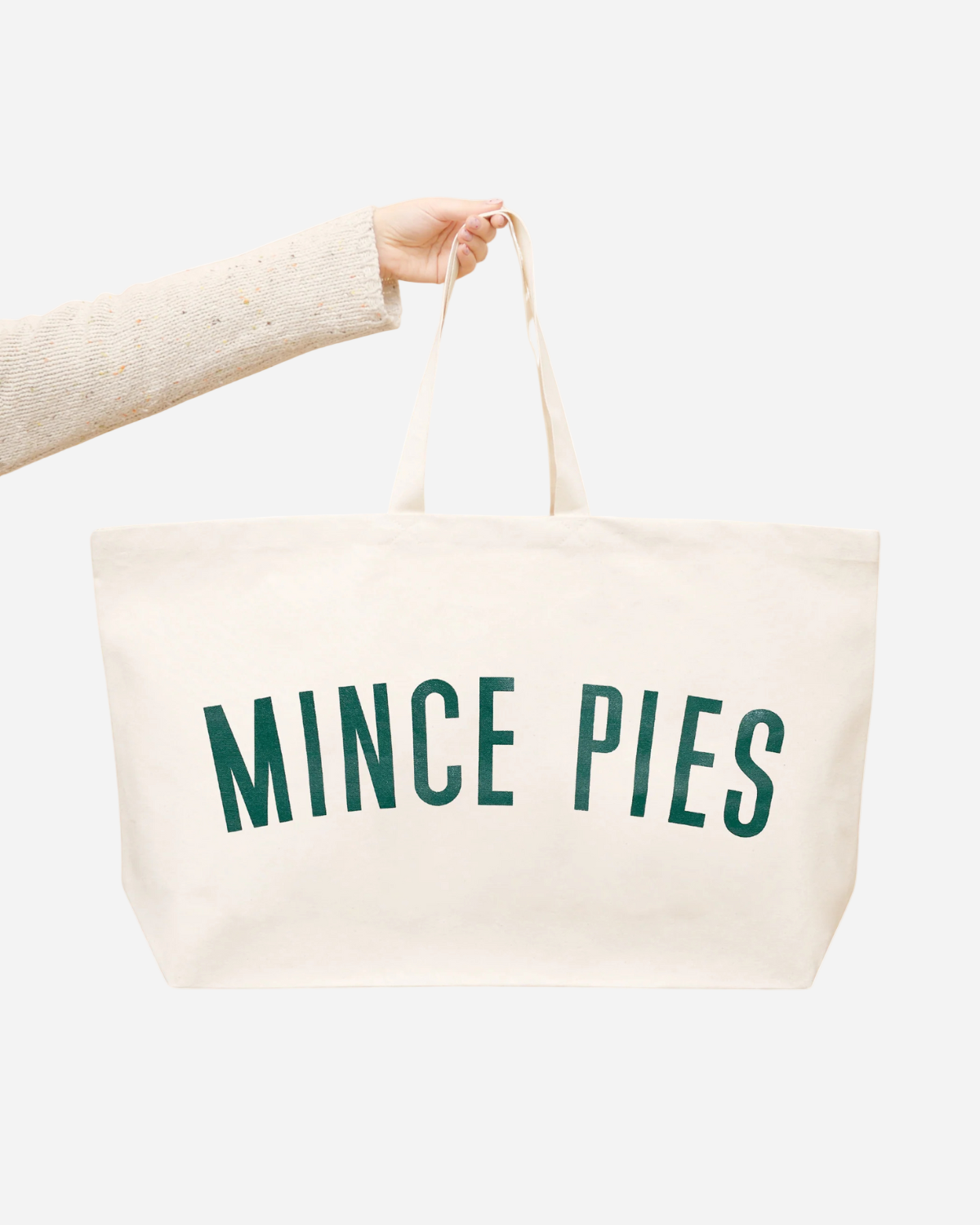 Beige tote bag with 'Mince Pies' text held by a person on a white background