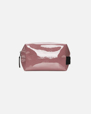 A dusty rose pink glossy patent leather cosmetic pouch with a black zipper pull and side tab, shown on a plain white background.