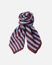 A lightweight striped scarf with alternating dark red and light blue horizontal bands, styled in a loose knot against a plain white background.