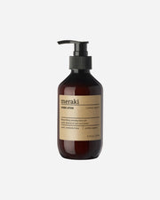 A pump bottle of Meraki Northern Dawn hand lotion with a brown tint and a label with the product name and organic certification.