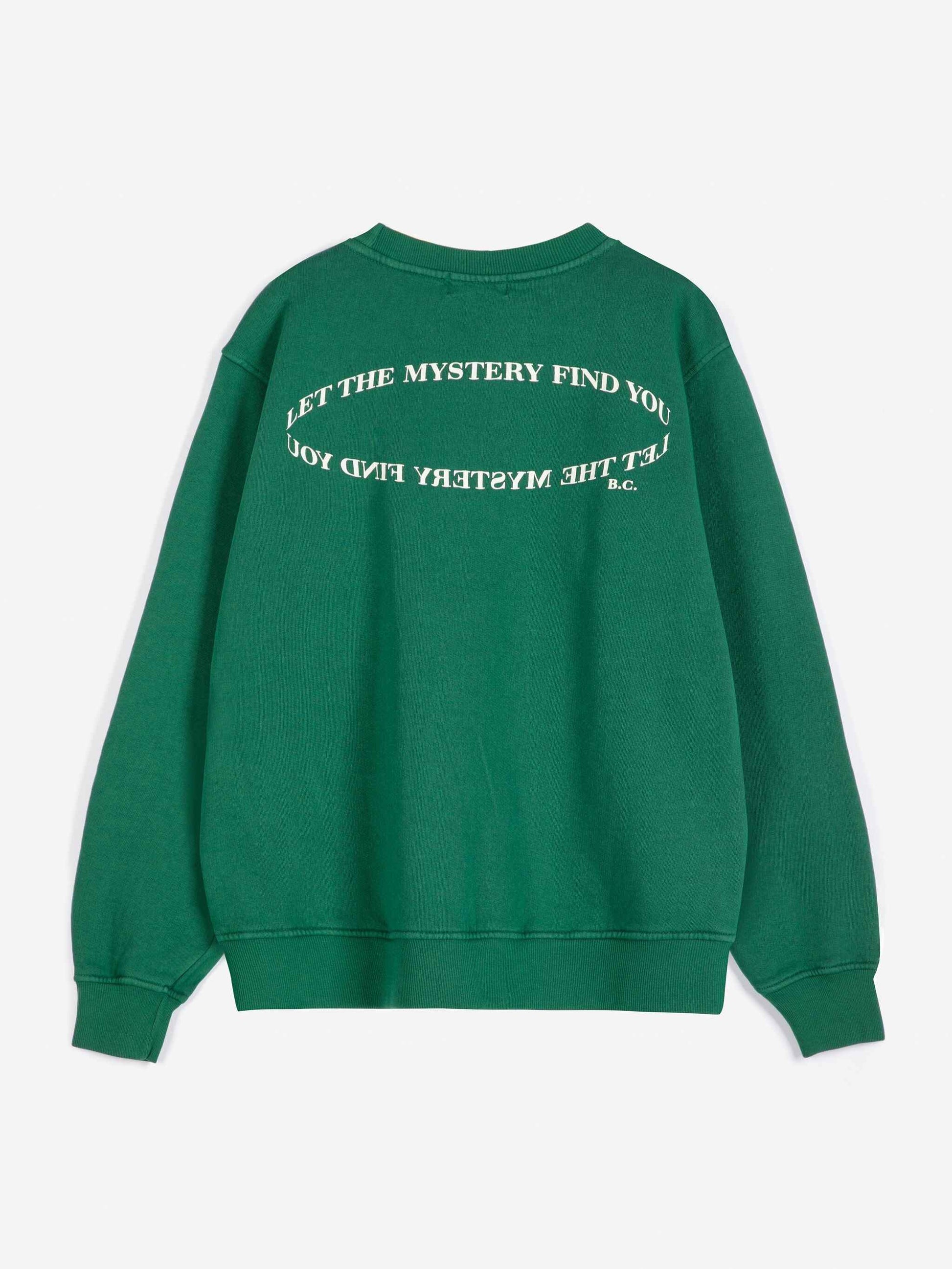 A green crewneck sweatshirt shown from the back, featuring white text that reads 'LET THE MYSTERY FIND YOU' in a circular design.