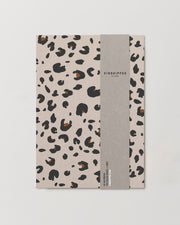 Notebook with leopard print cover and gray spine on a light gray background