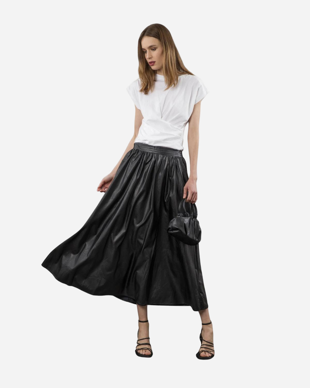 Woman wearing a black faux leather skirt and white top on a white background