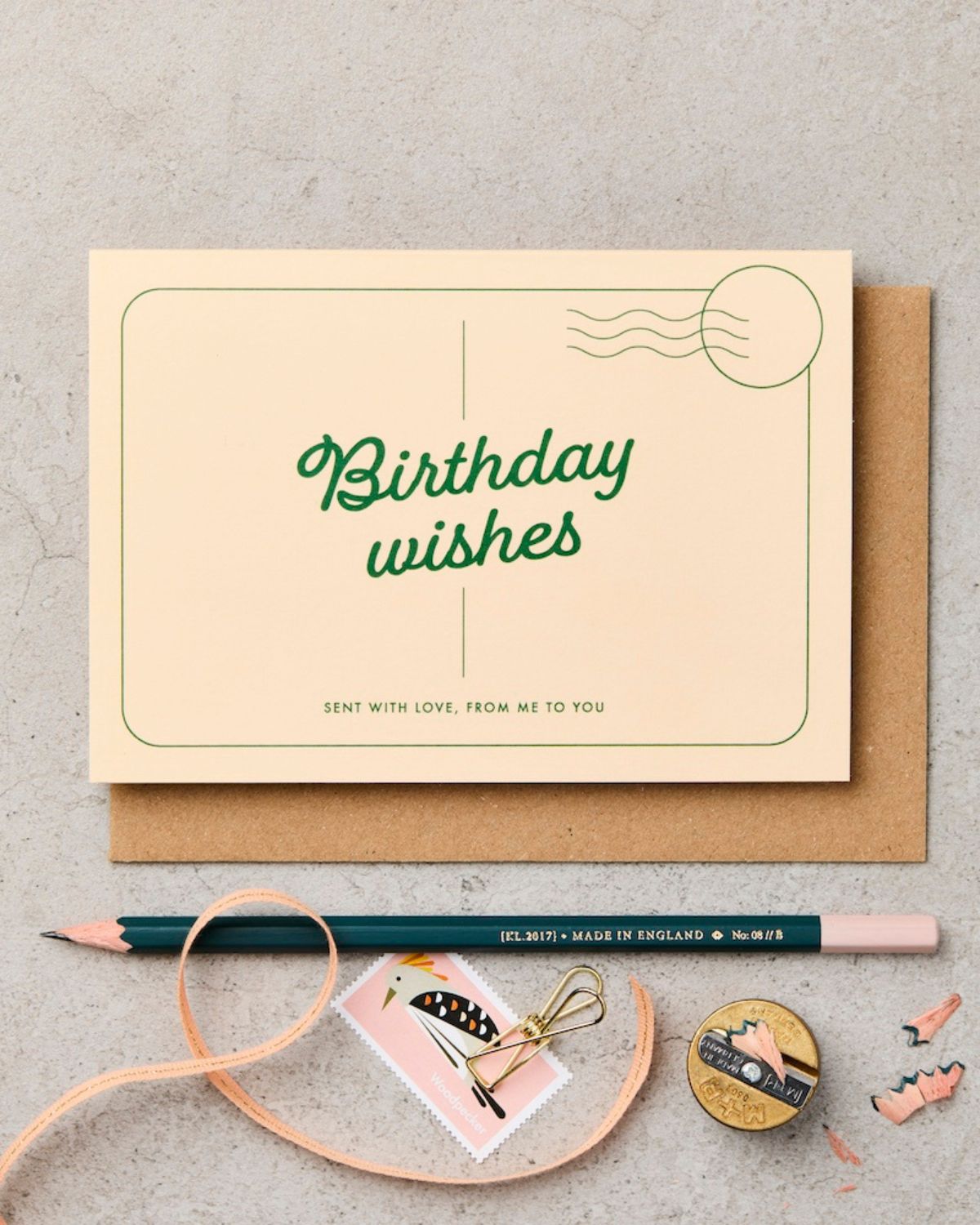 Birthday card with 'Birthday wishes' text on a gray surface with stationery items.