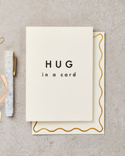 Card with 'HUG in a card' text on a textured surface