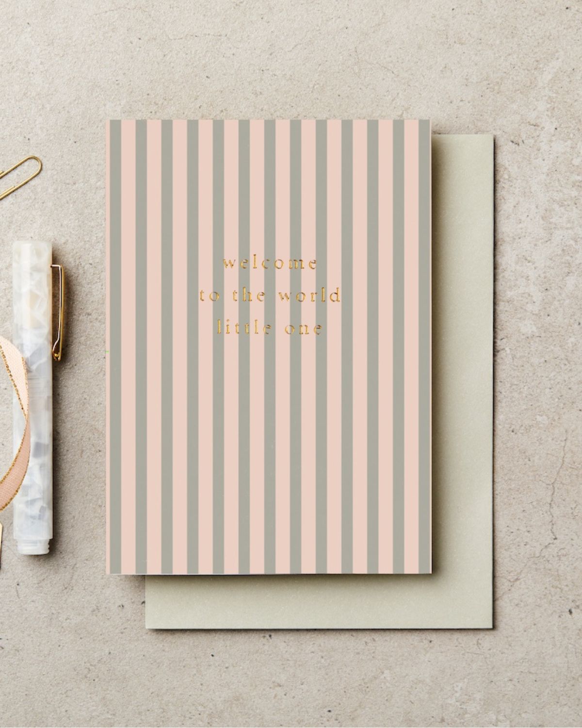 Striped card with 'welcome to the world little one' text on a beige background