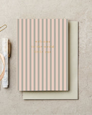 Striped card with 'welcome to the world little one' text on a beige background