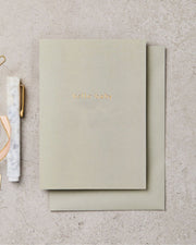 Green notebook with 'Hello World' on a textured surface