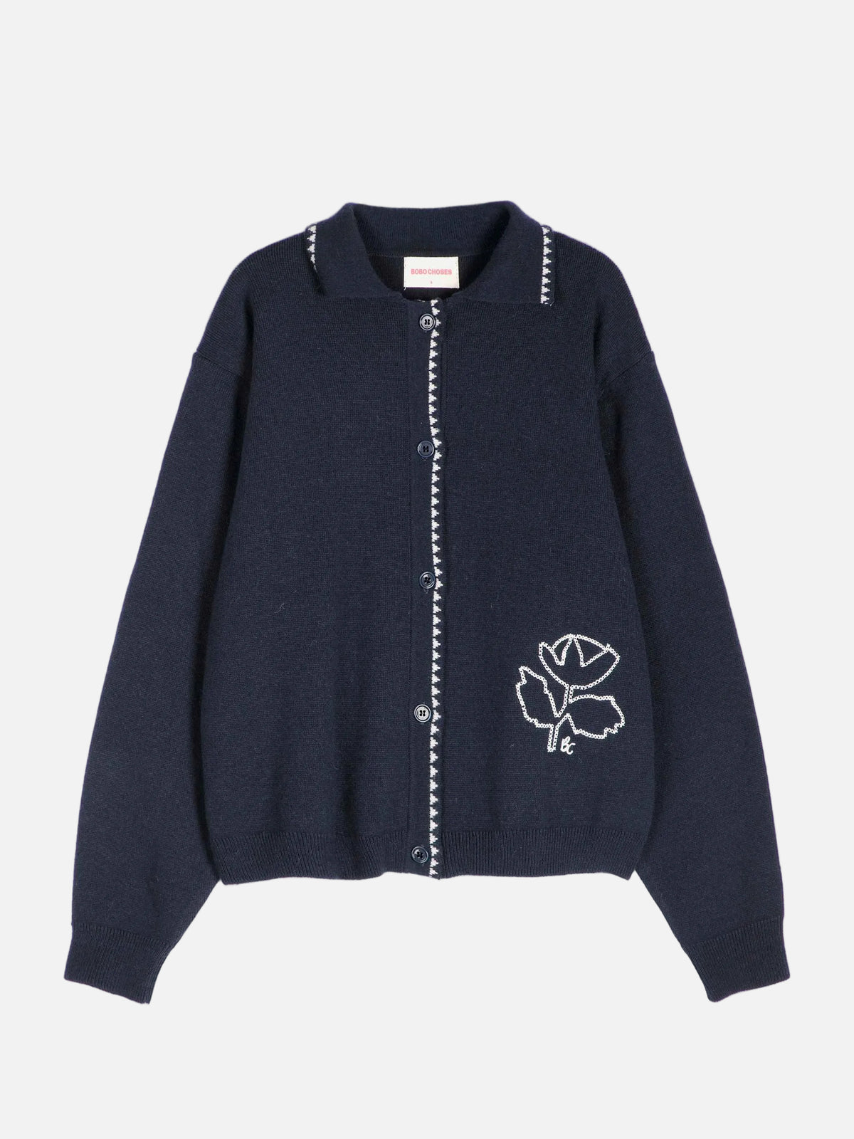 A dark navy blue knit cardigan sweater with white embroidered details, including a rose motif on the lower left chest and white bead trim along the collar and front button placket, shown against a plain light gray background.