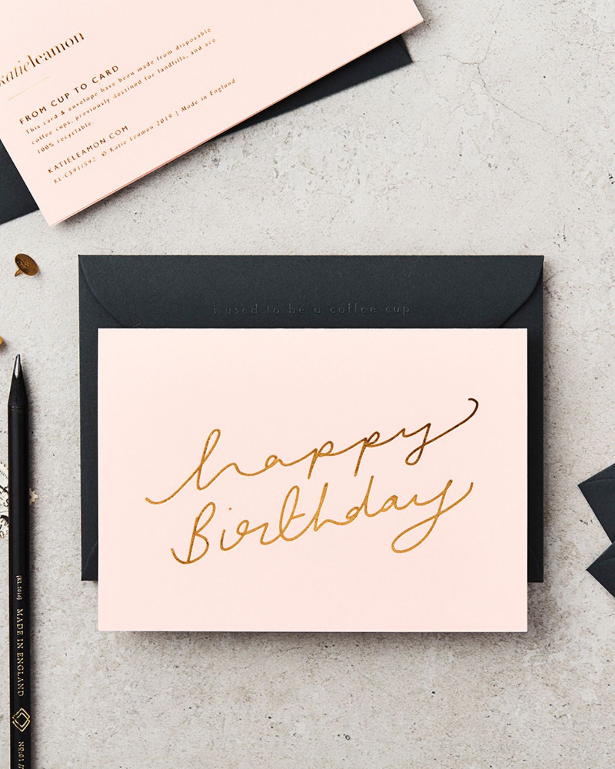 Pink birthday card with gold text on a gray surface