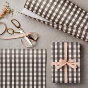 Gray and white checkered gift wrap with a ribbon and scissors on a gray surface