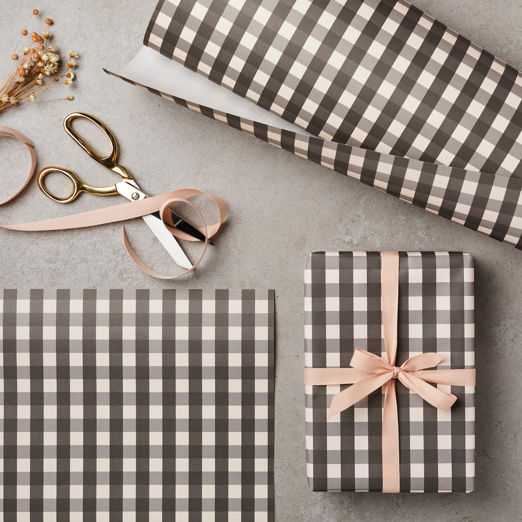 Gray and white checkered gift wrap with a ribbon and scissors on a gray surface