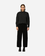 Person wearing a black checkered shirt and black pants on a white background