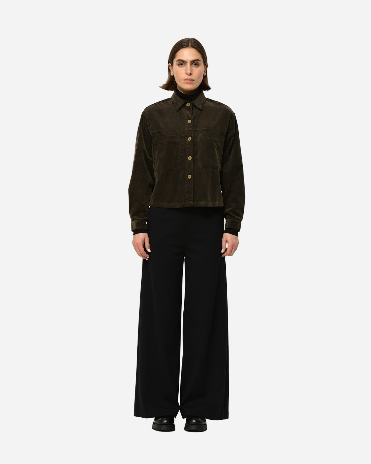 MODEL wearing a dark brown corduroy jacket and black pants on a white background