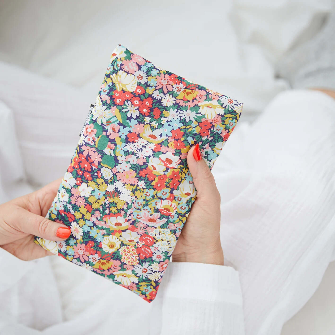 Hand holding a colorful floral hot water bottle