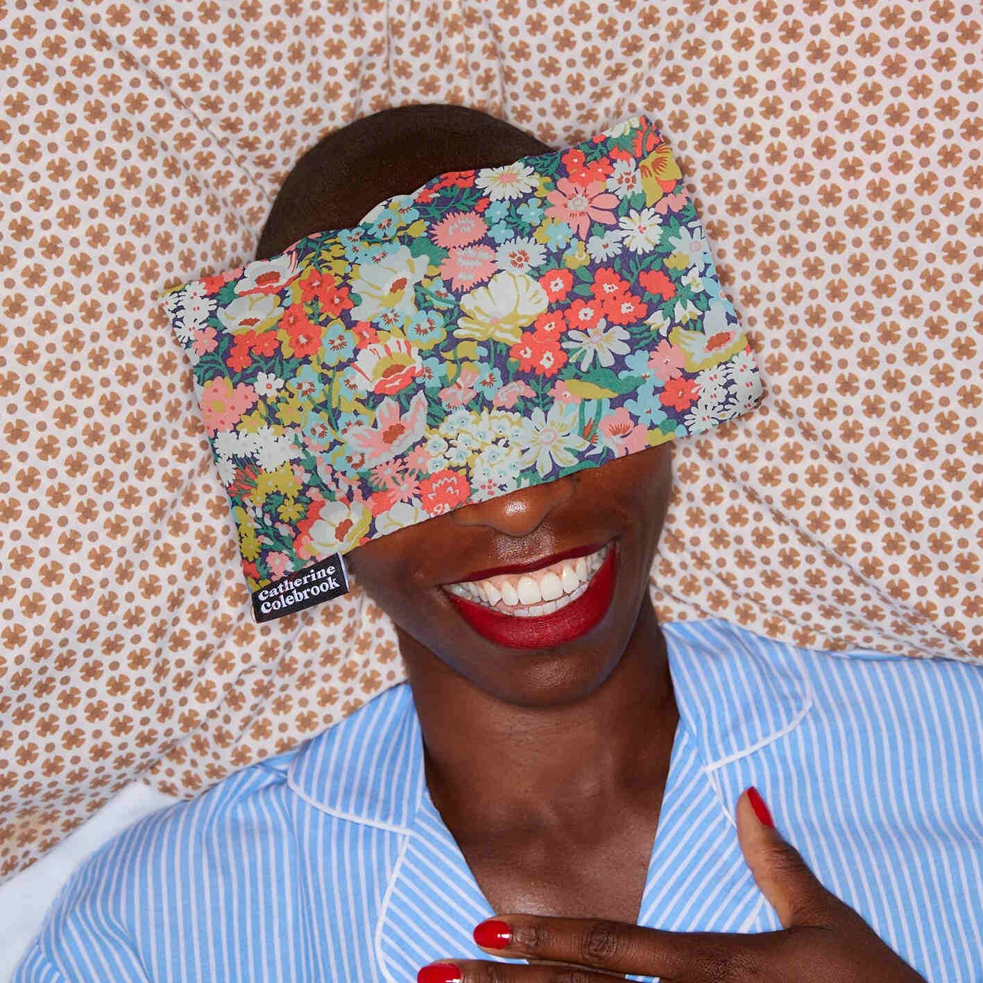 Person wearing a floral headband with a visible brand name, against a patterned wall.