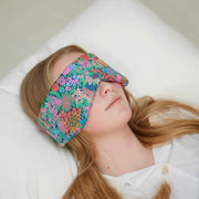 Person wearing a colorful floral sleep mask on a white pillow