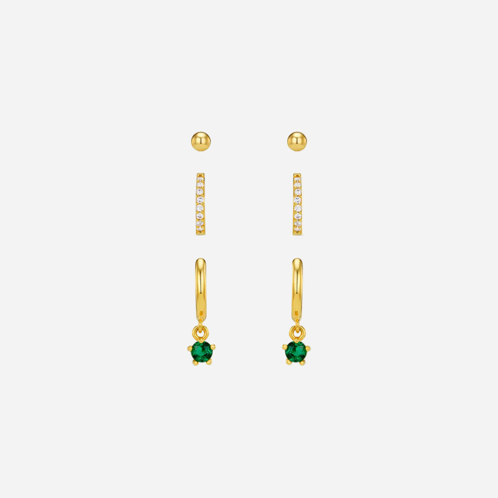 Set of gold earrings with green gemstones on a white background