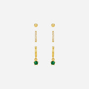 Set of gold earrings with green gemstones on a white background