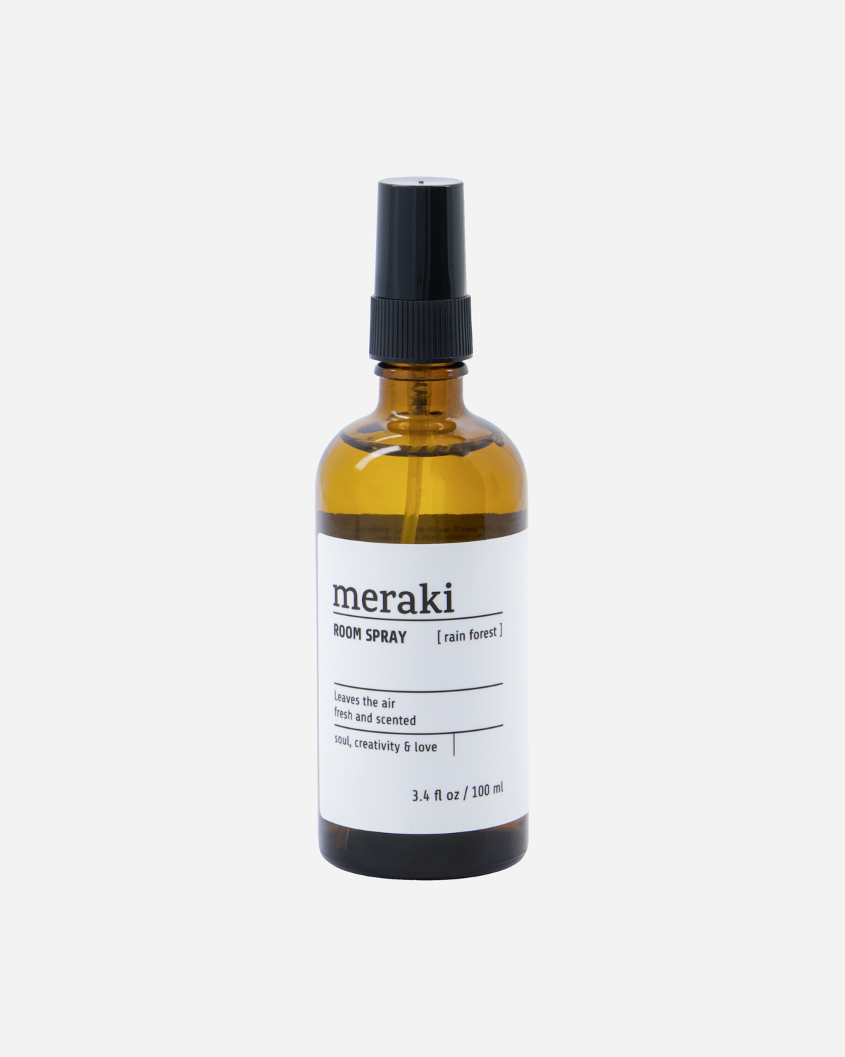 A glass bottle of Meraki room spray with a black spray nozzle. The label shows the product name and the scent, Rain Forest.