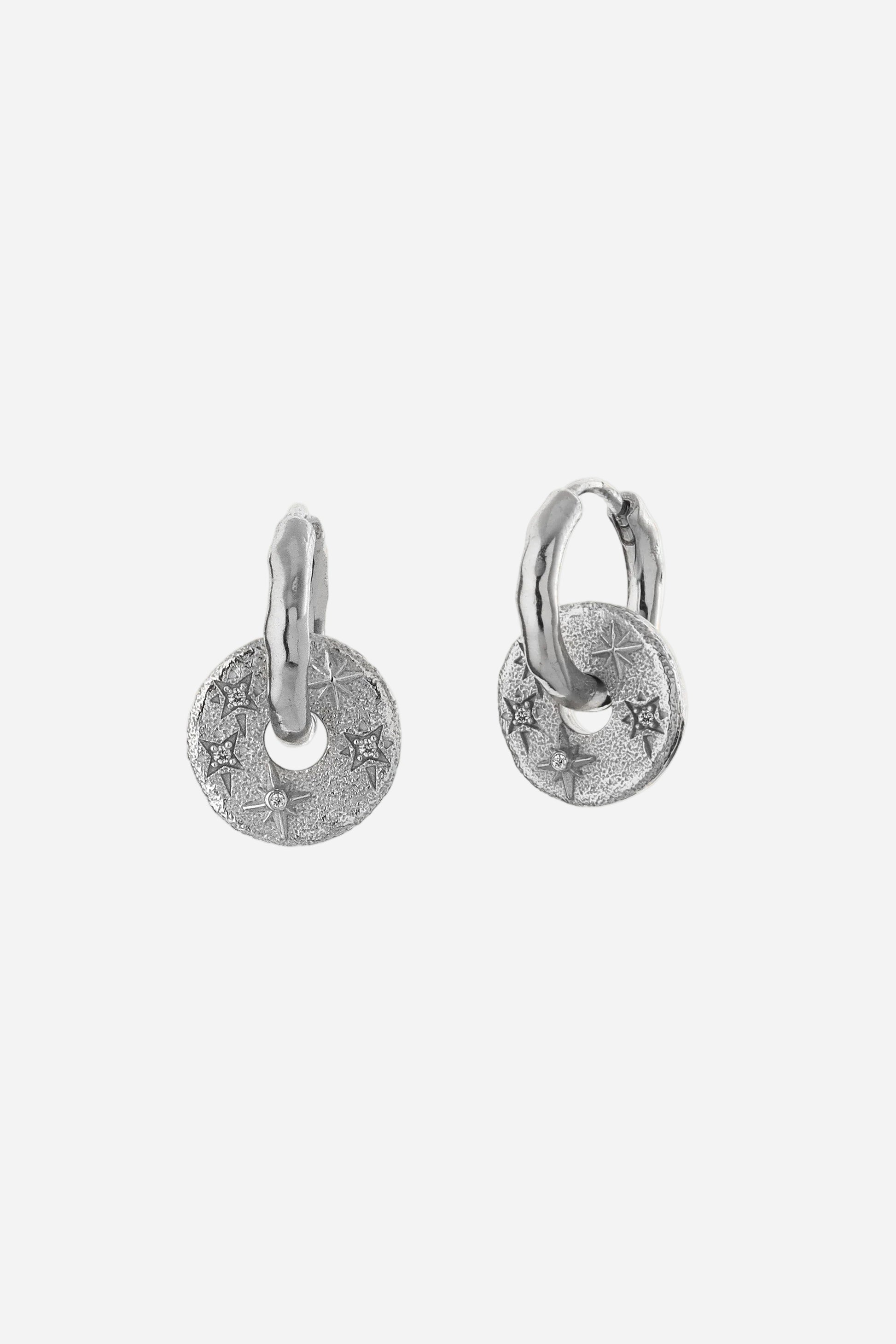 Pair of silver hoop earrings with round tags on a light gray background