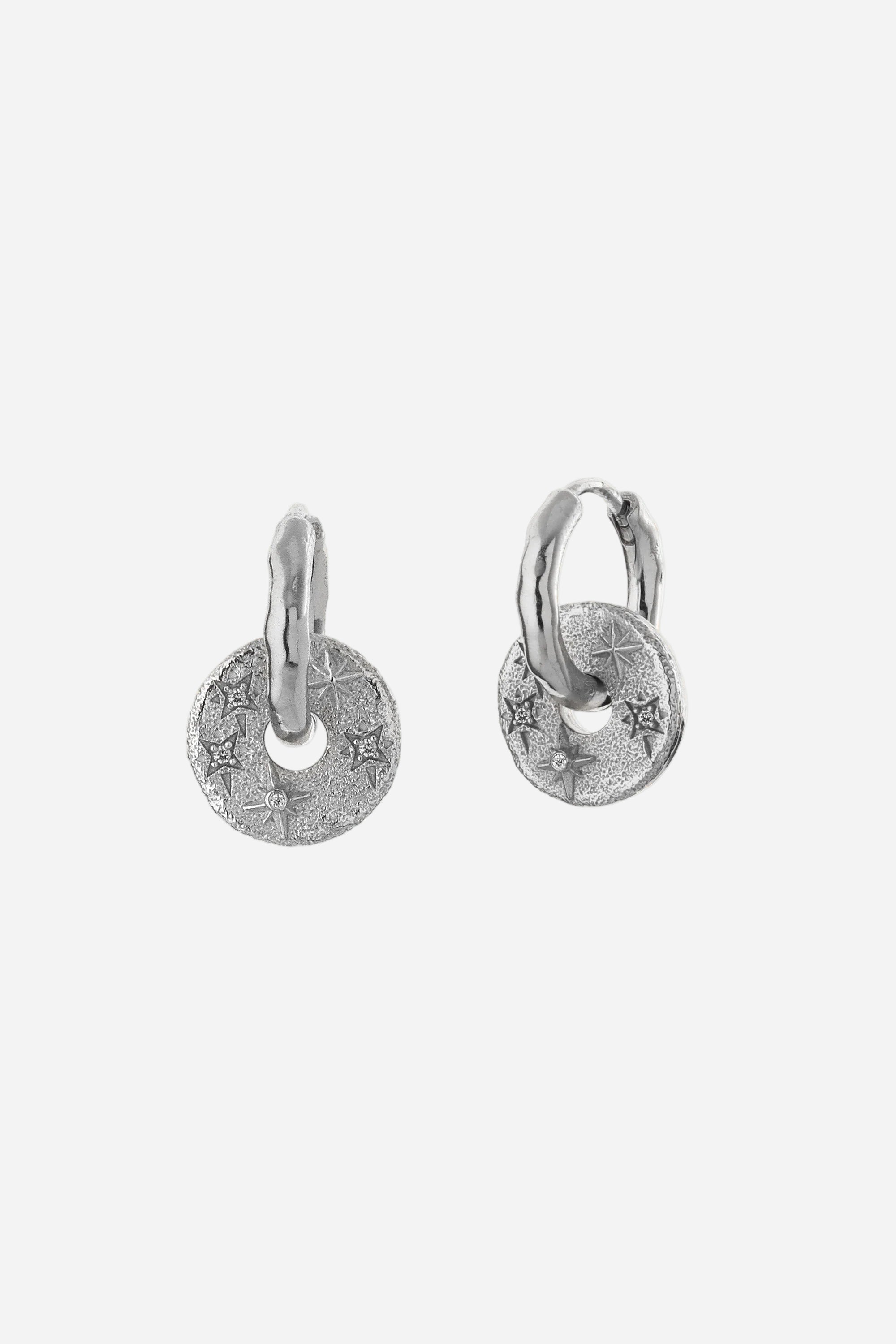 Pair of silver hoop earrings with round tags on a light gray background