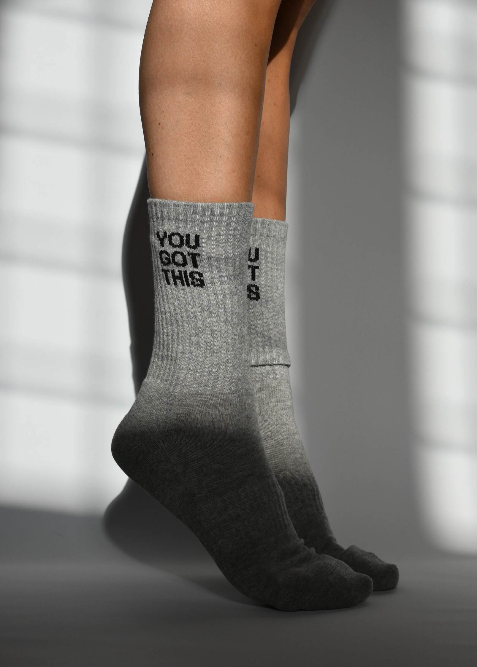 A pair of gray crew-length socks with the text 'YOU GOT THIS' printed on the side, featuring arch support and a cushioned heel and toe.