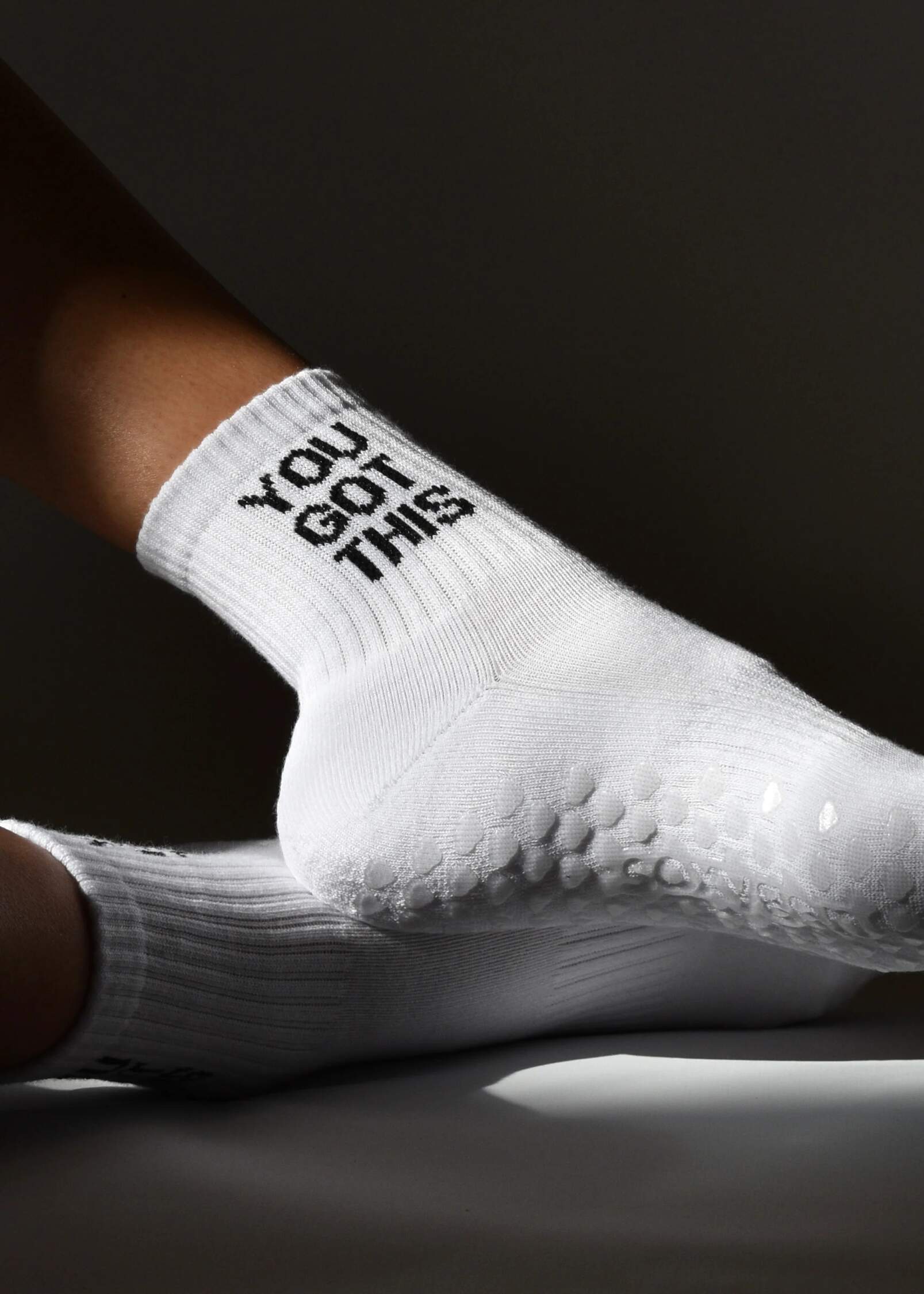A white grip sock with 'YOU GOT THIS' text on the ankle area, featuring a non-slip sole, arch support, and elasticated stretch.