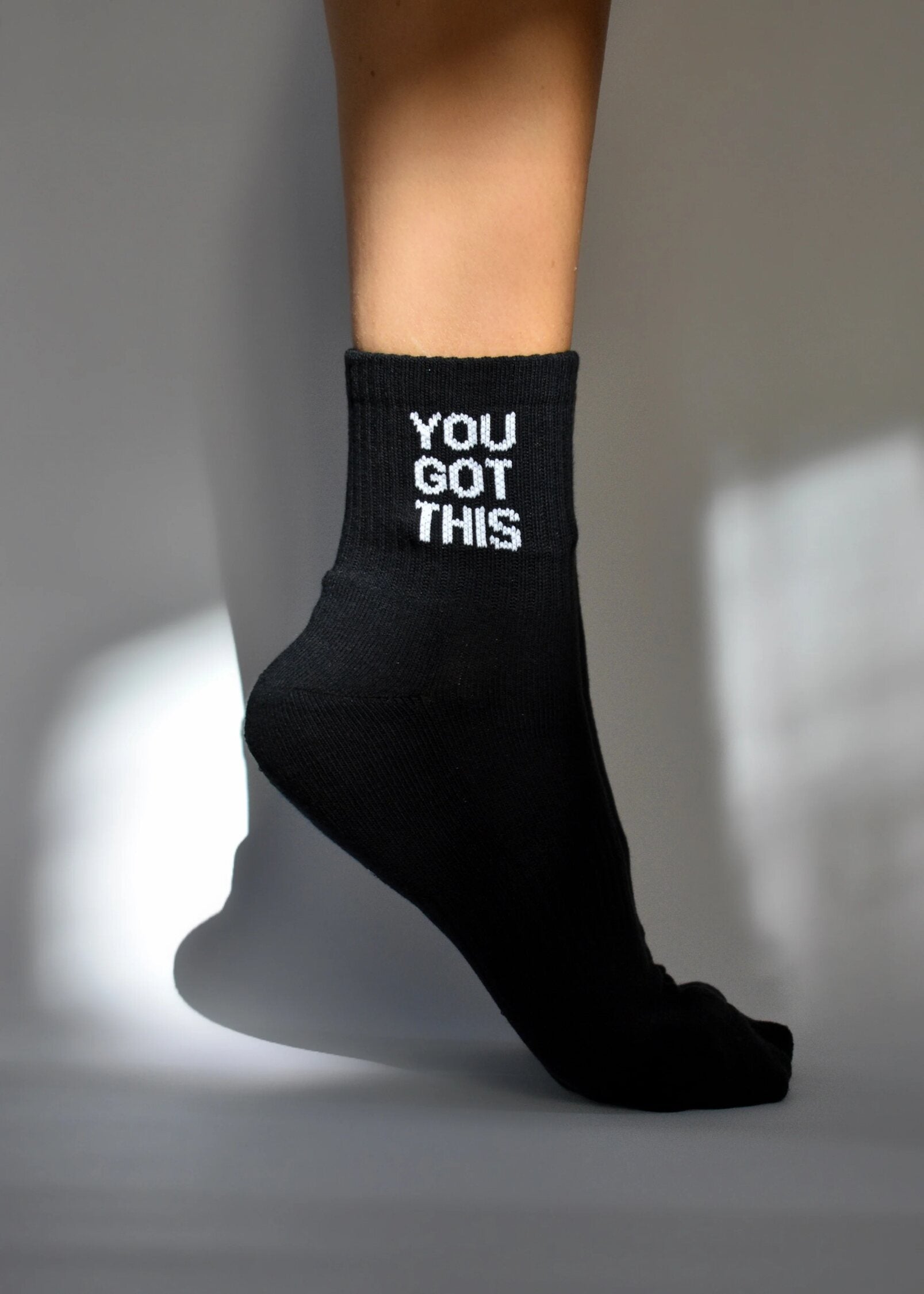 A black crew-length sock with 'YOU GOT THIS' text in white on the upper part, worn on a person's foot.