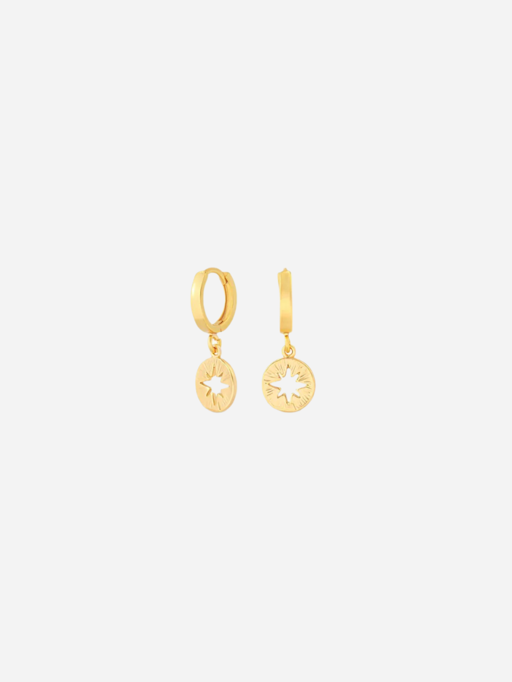 A pair of gold huggie earrings with a small star charm attached to the hoop.