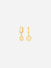 A pair of gold huggie earrings with a small star charm attached to the hoop.