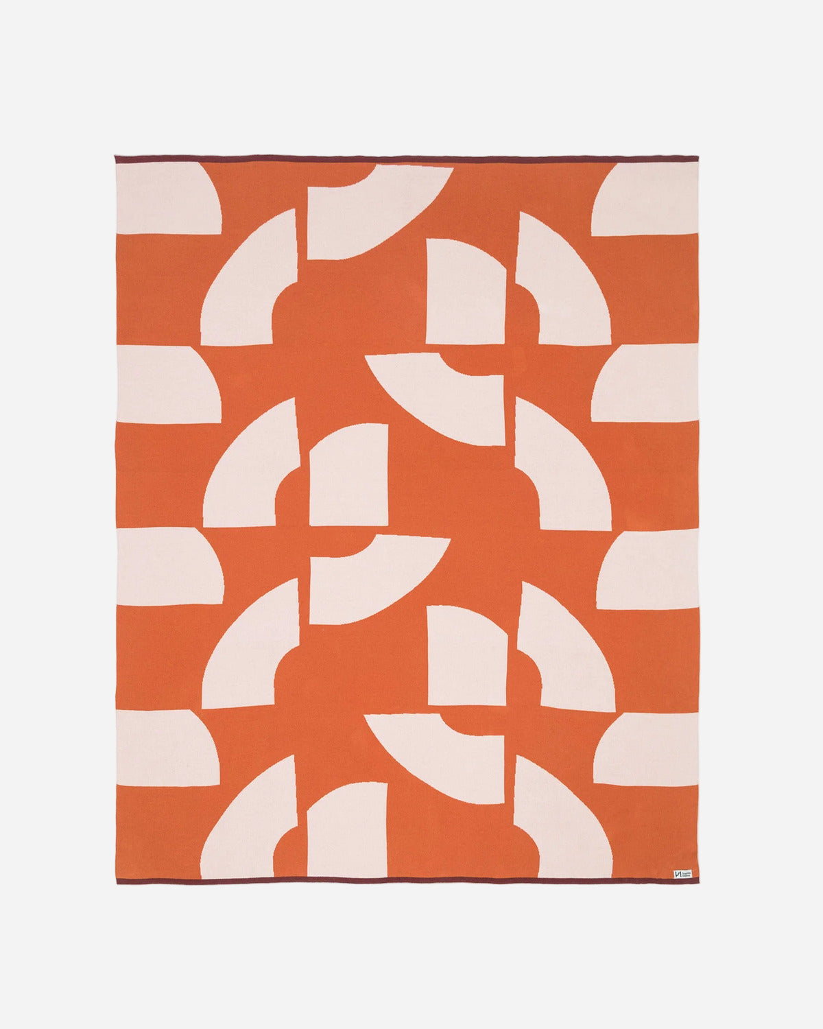 Orange blanket with white geometric pattern on a white background
