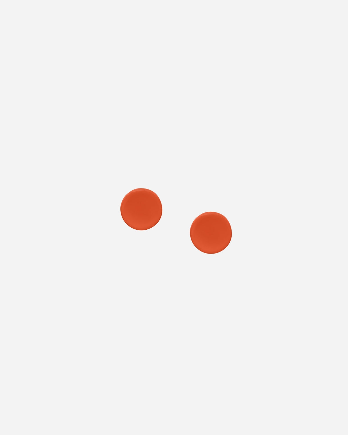 Two orange stud earrings on a white background