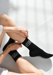 A person seated with 'I HAVE NOTHING TO WEAR' text on a black sock worn on their left foot.